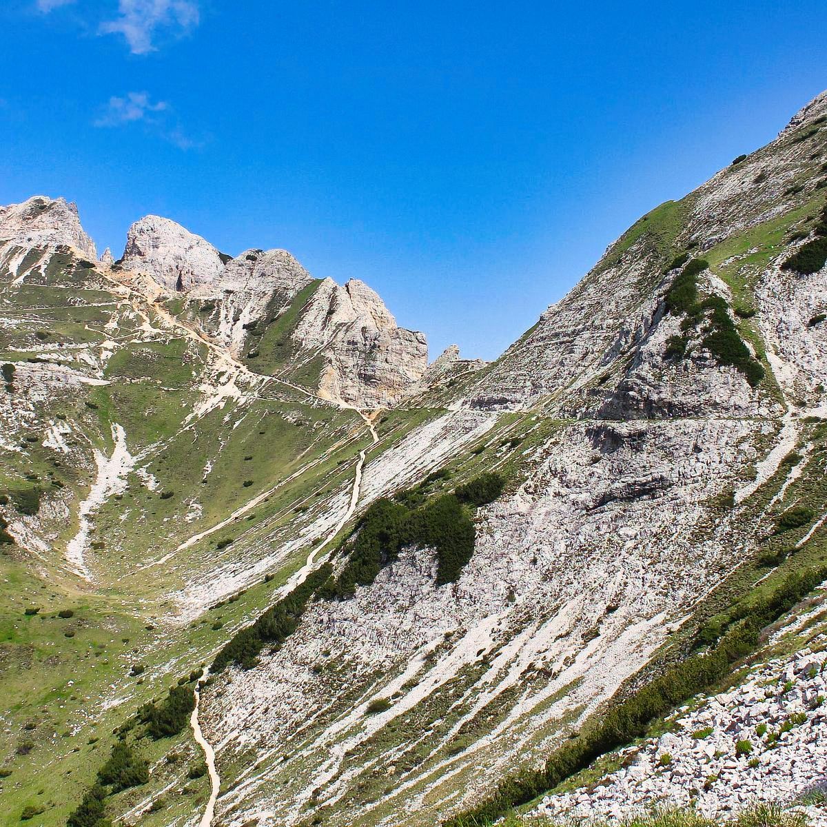 Una montagna ricoperta di erba e rocce con un cielo azzurro sullo sfondo.