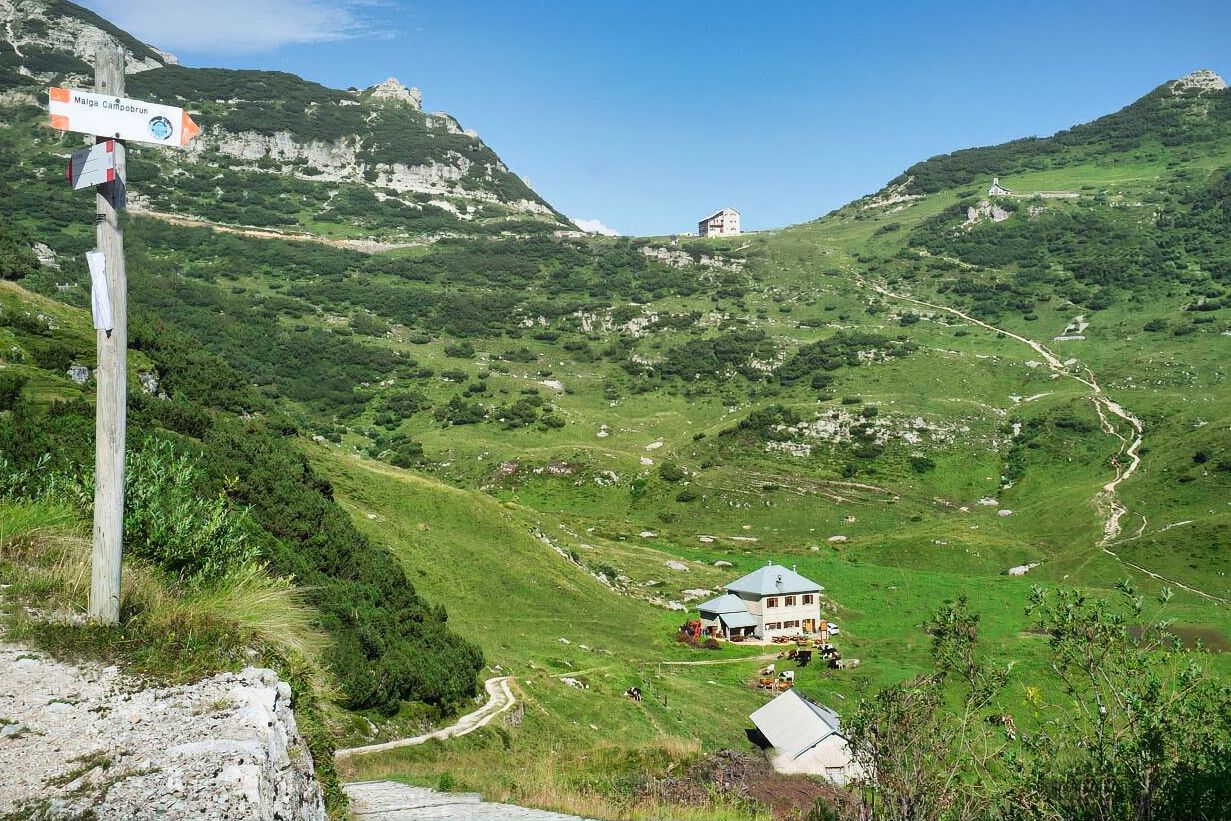 Un cartello su un palo indica la strada verso una casa in montagna.
