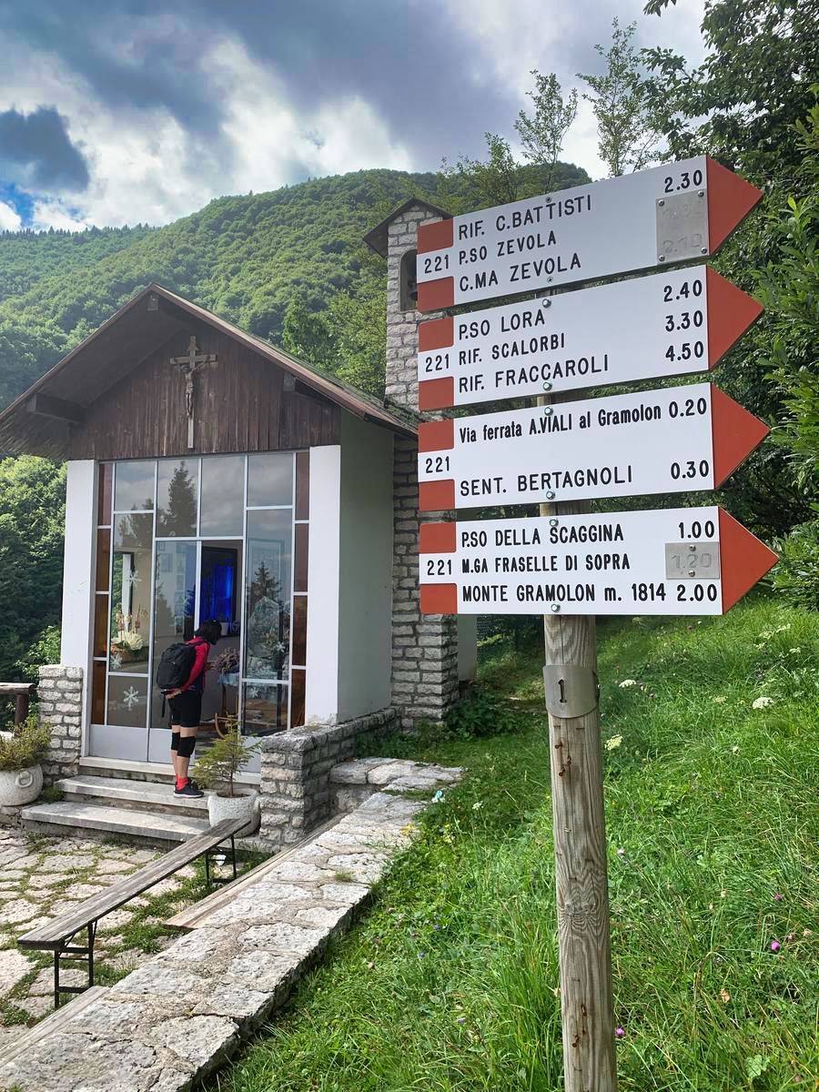 Una persona è in piedi davanti a un piccolo edificio con un cartello davanti.