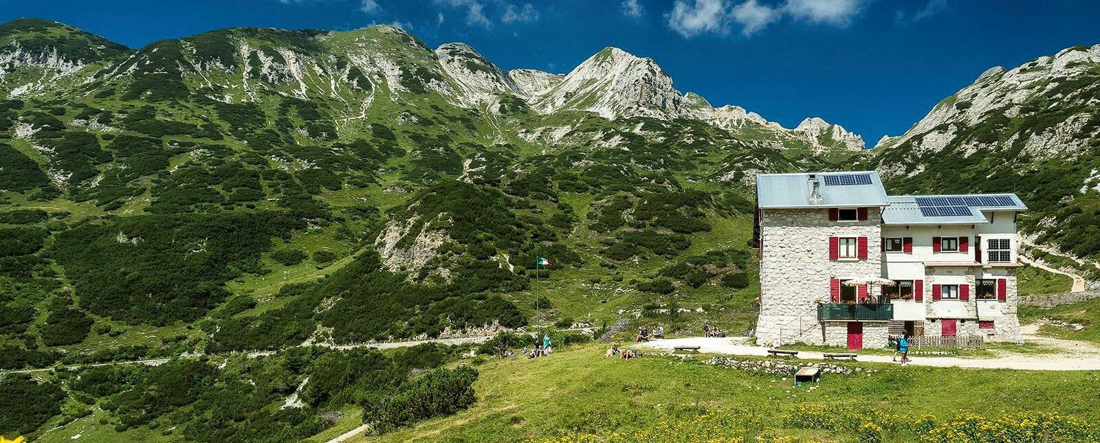 Una casa è situata in cima ad una collina erbosa tra le montagne.
