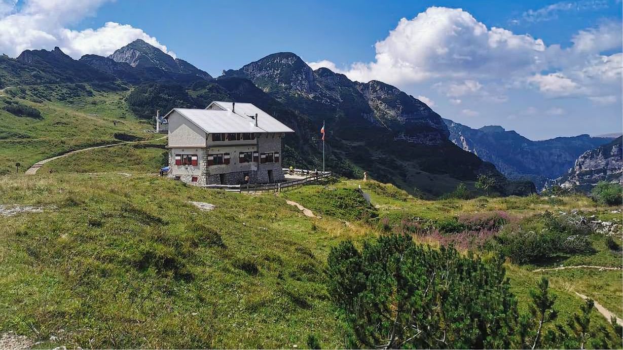 Una casa è situata in cima ad una collina erbosa tra le montagne.
