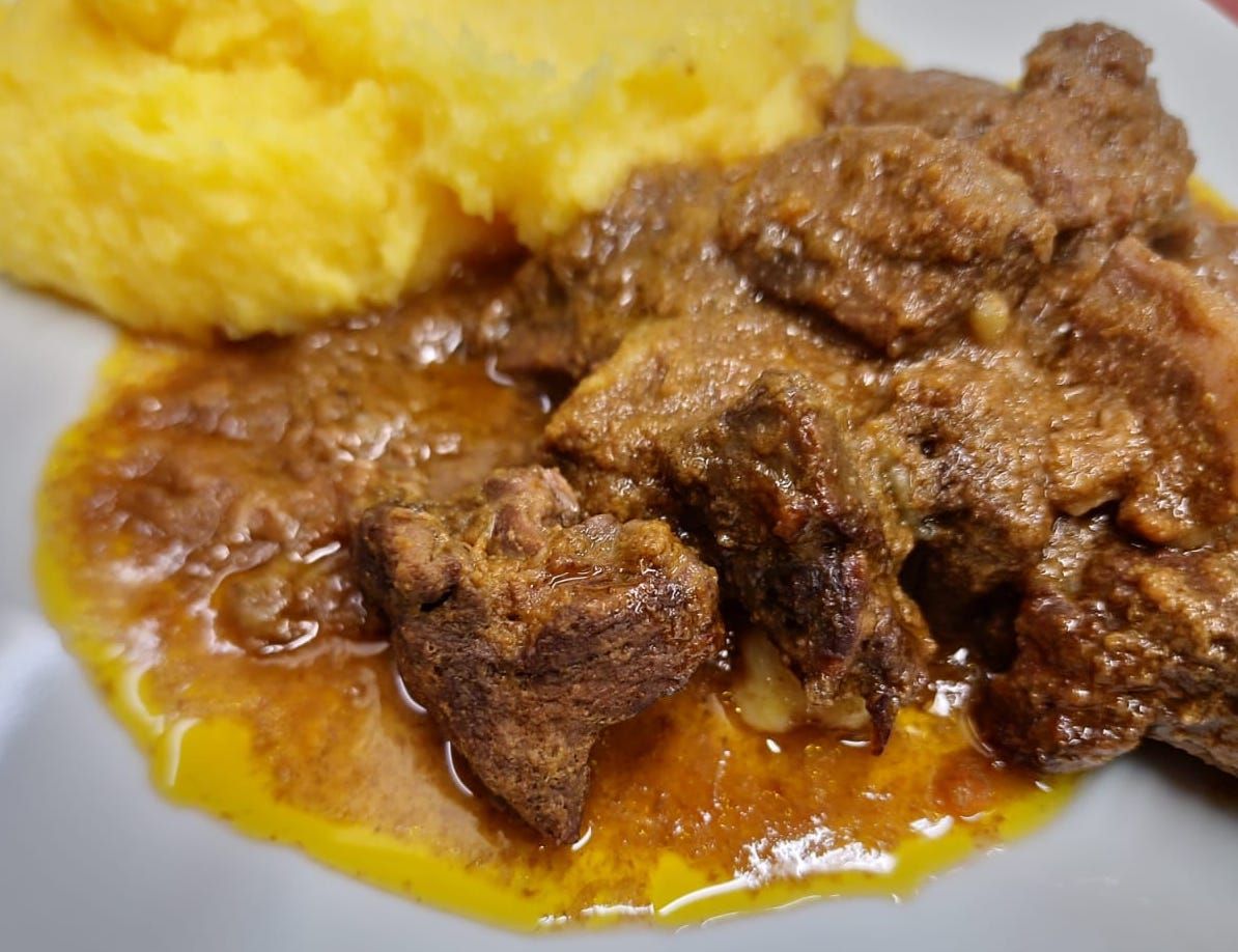 A white plate topped with meat and mashed potatoes.