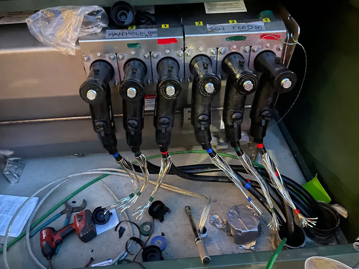 Electrical panel with multiple black connectors and colored wires, open in an outdoor setting.