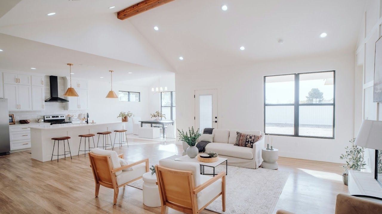 Bright, open-concept living space with light wood floors, white walls, and kitchen.