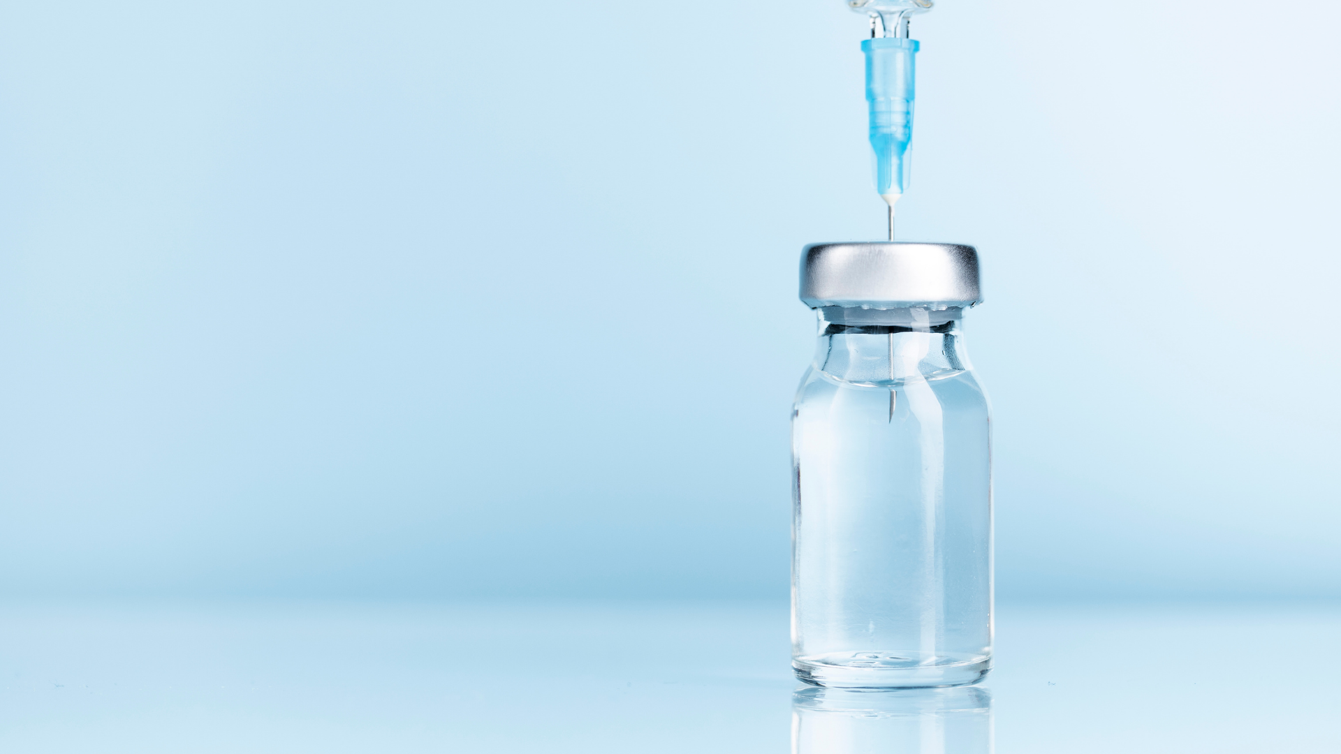 A syringe is being inserted into a bottle of liquid.