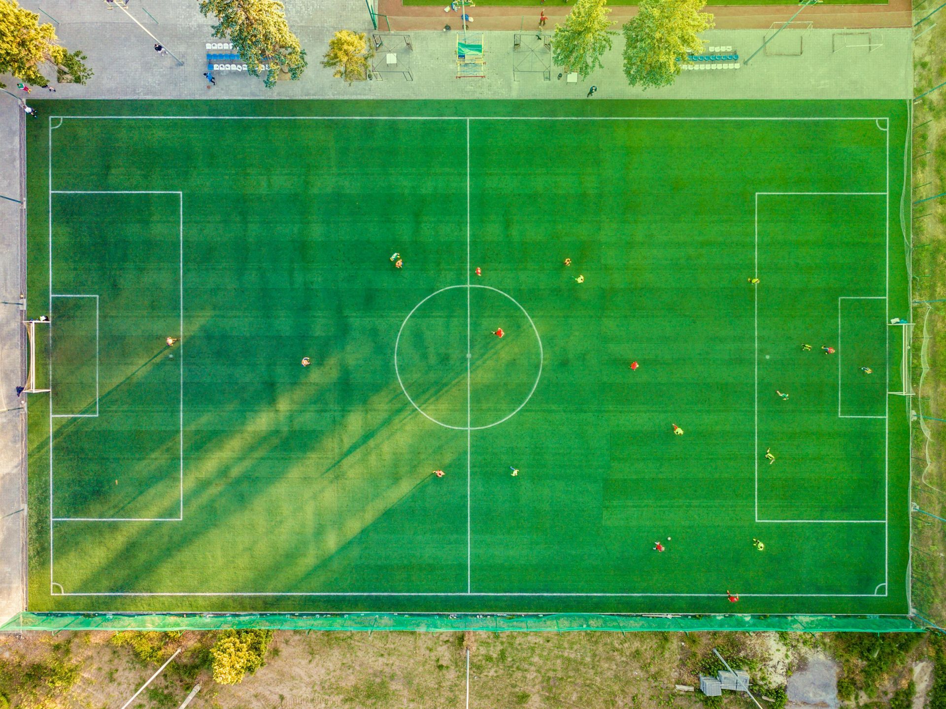 Soccer game on a green field; players in motion, some orange shirts.