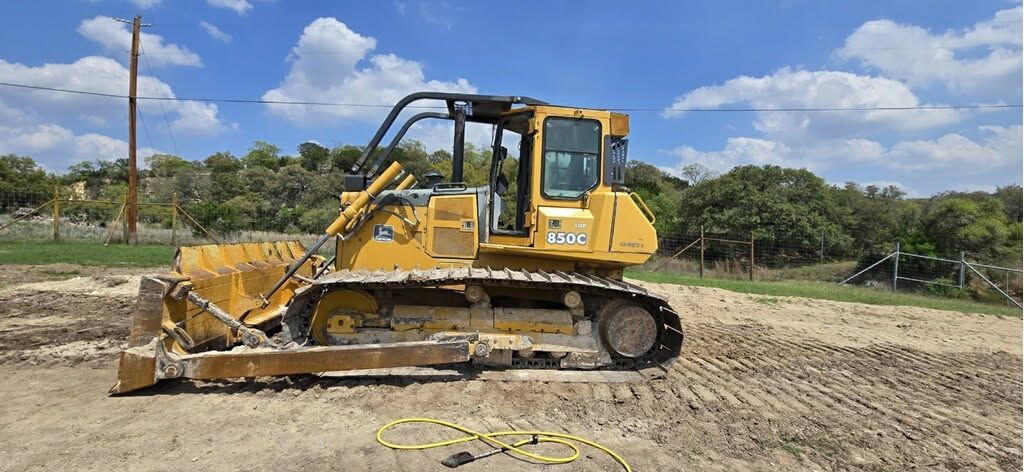 A bulldozer is sitting in the middle of a dirt field.