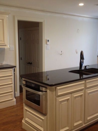 Kitchen with white cabinets, black countertop, built-in oven, and a sink.