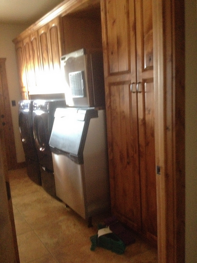 Laundry room with wooden cabinets and appliances including a washing machine and ice machine.