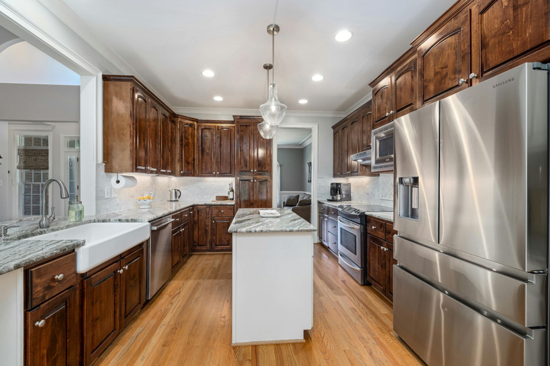A kitchen with dark wood cabinets, stainless steel appliances, and a white island.
