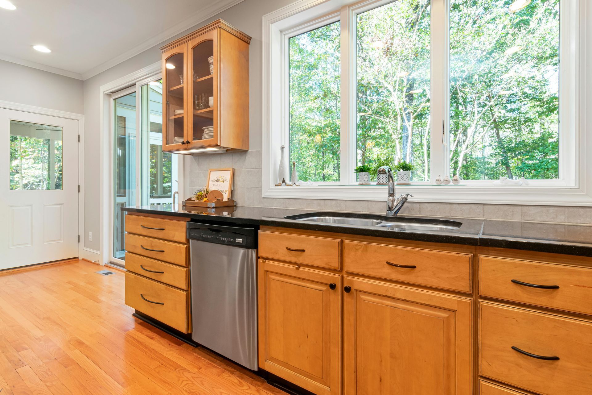 Kitchen with wooden cabinets, stainless steel appliances, and a window overlooking greenery.