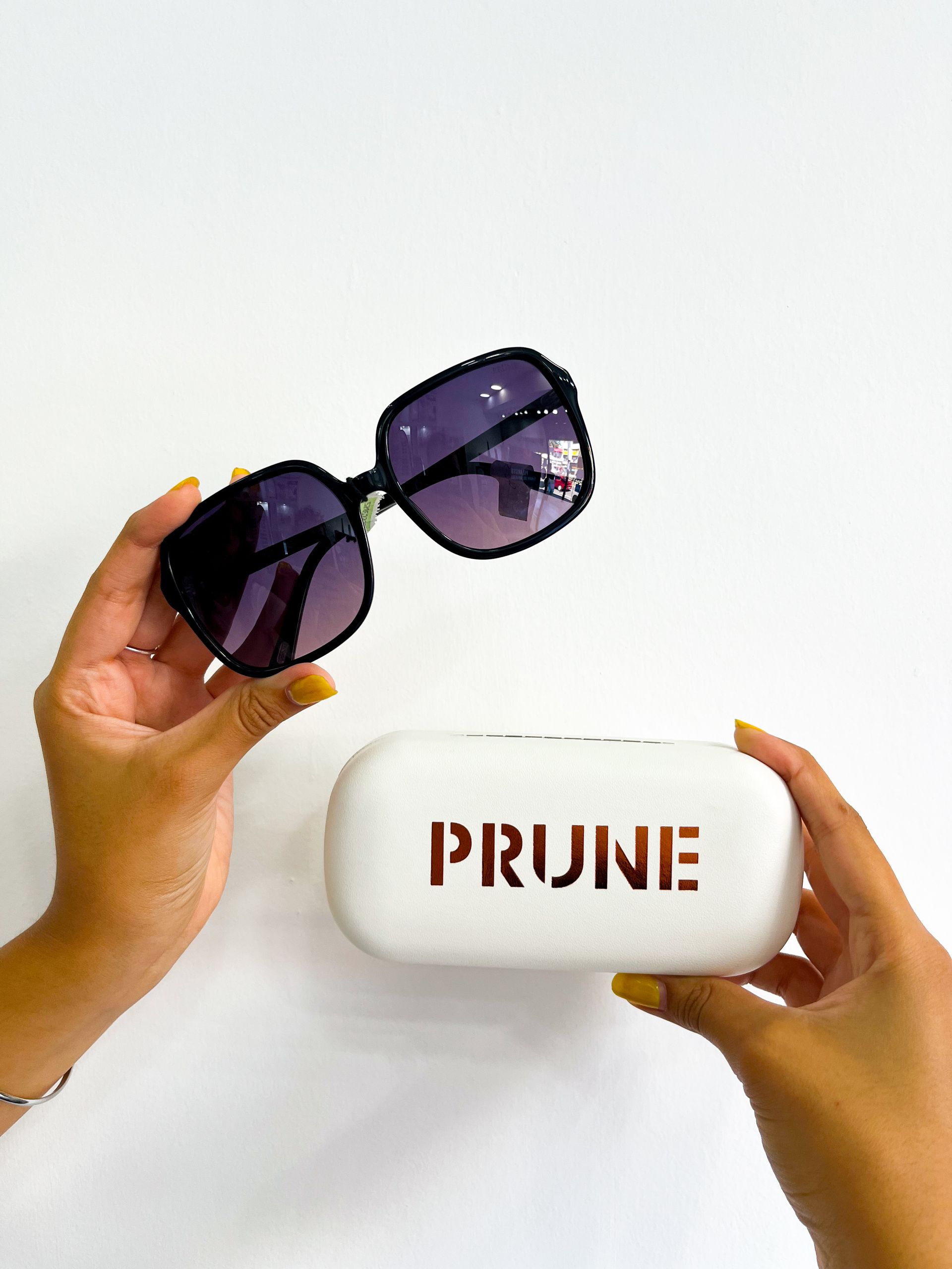 Persona sosteniendo unas gafas de sol y un estuche blanco con la marca 