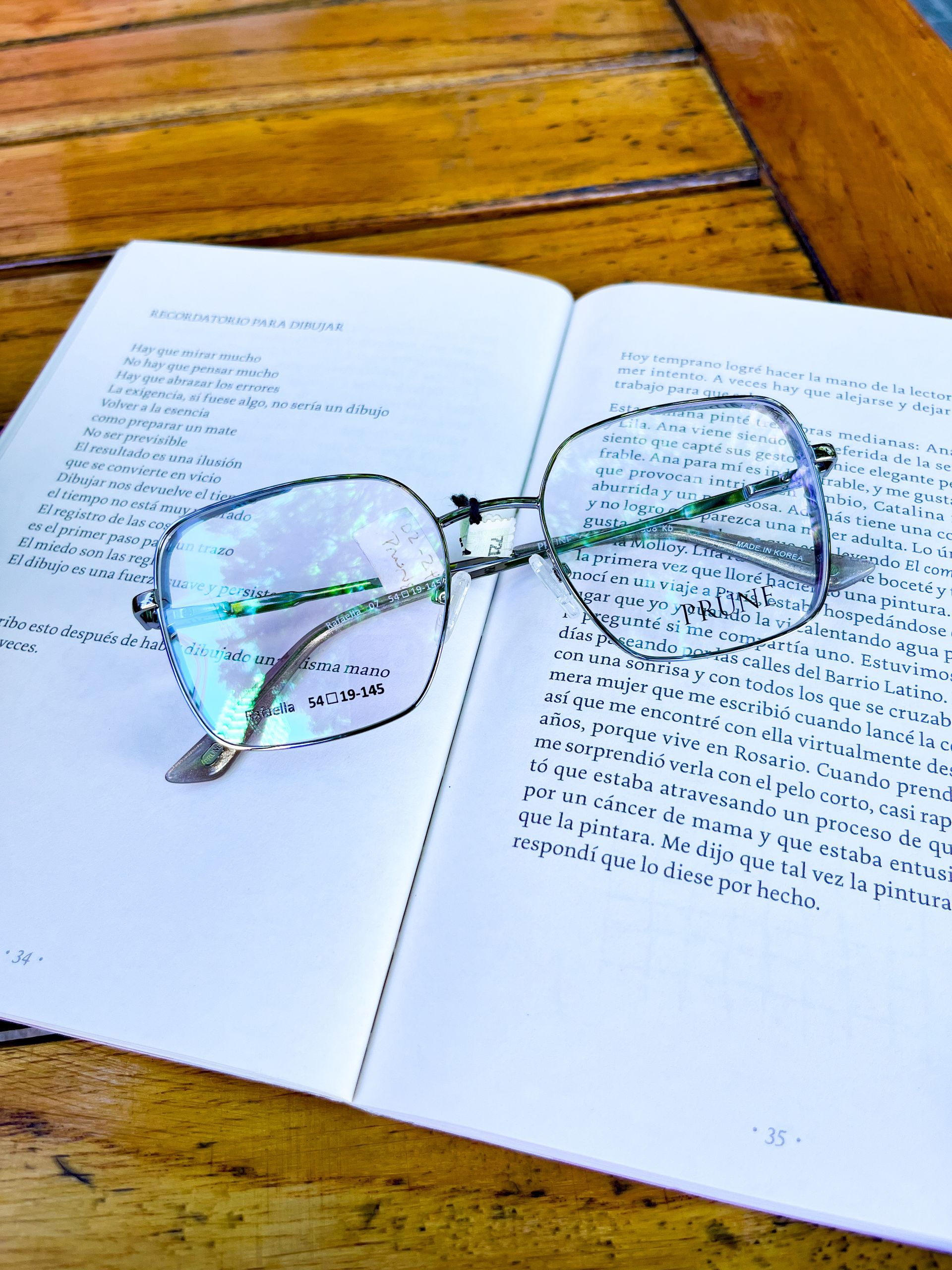 Los vasos descansan sobre un libro abierto, sobre una mesa de madera.
