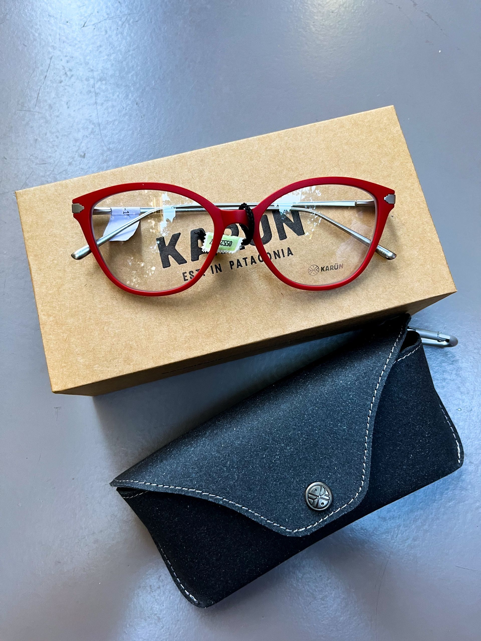 Gafas con montura roja en una caja con un estuche para gafas moteado en negro.