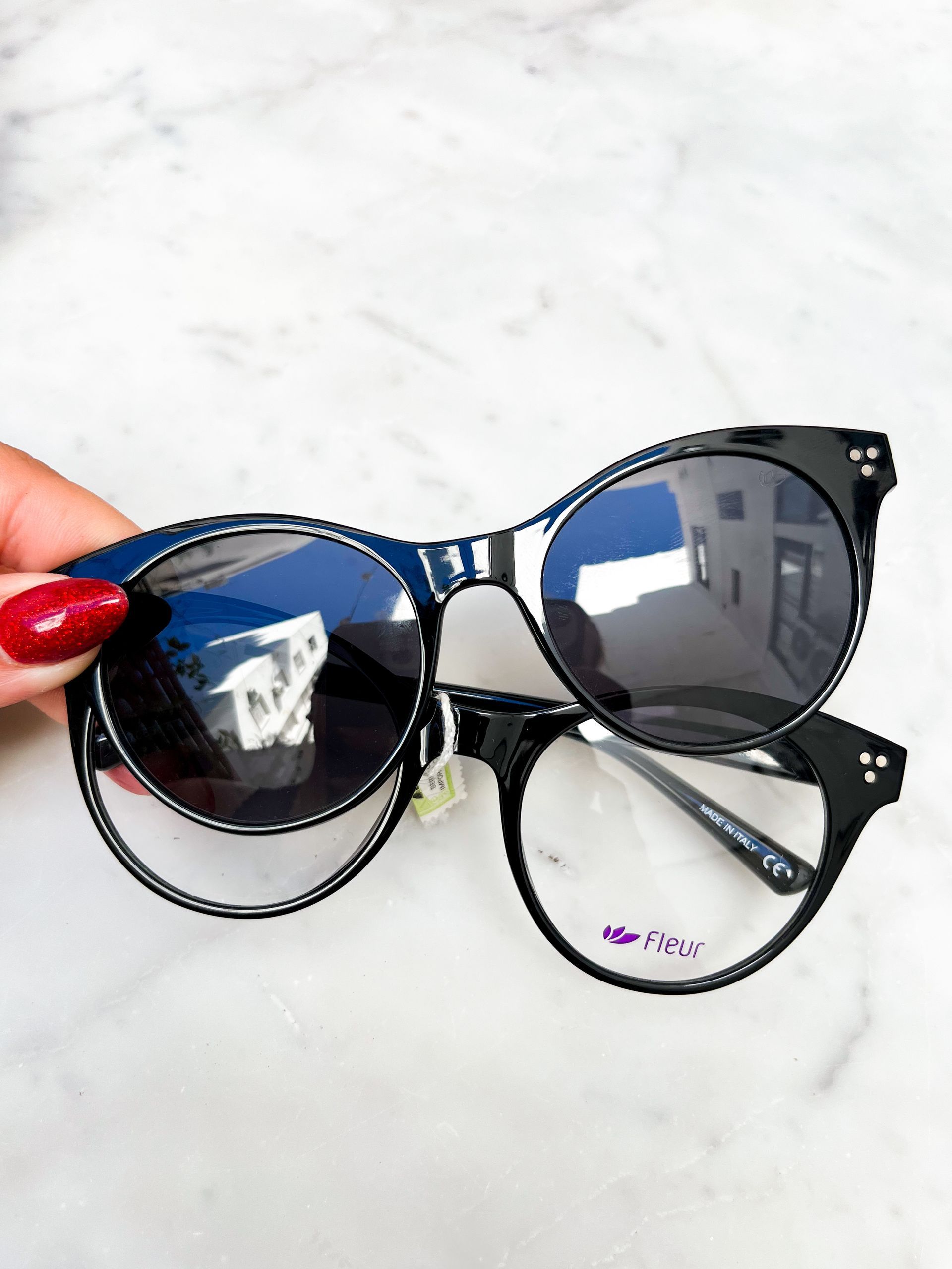 Montura de gafas de sol de color negro con lente tintada con clip, colocada sobre gafas con lentes transparentes