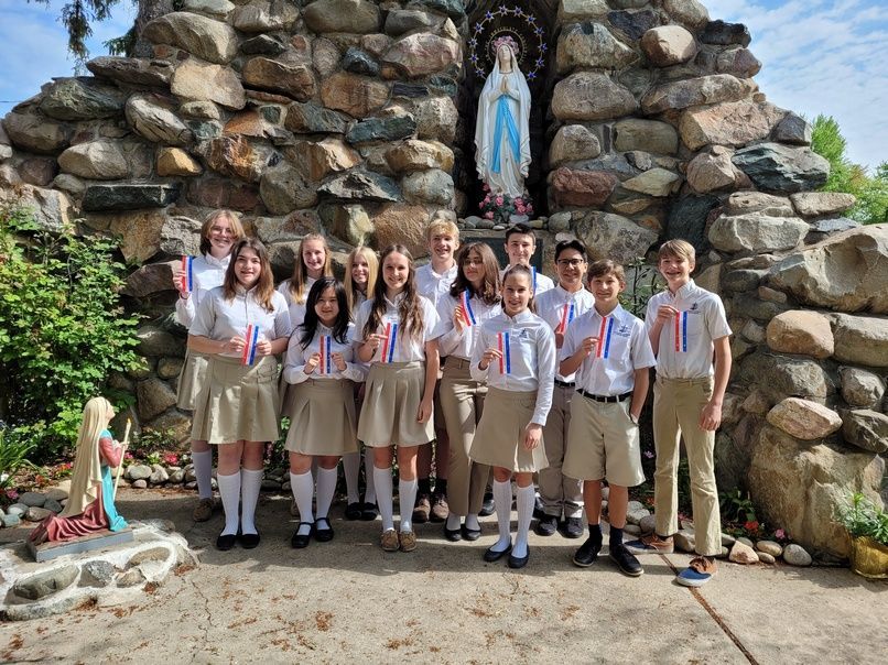A group of students from Immaculate Conception Catholic School posing in front of a statue of the Virgin Mary in Ira Township, MI.
