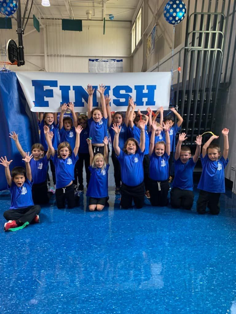 A group of children are posing in front of a sign that says finish.