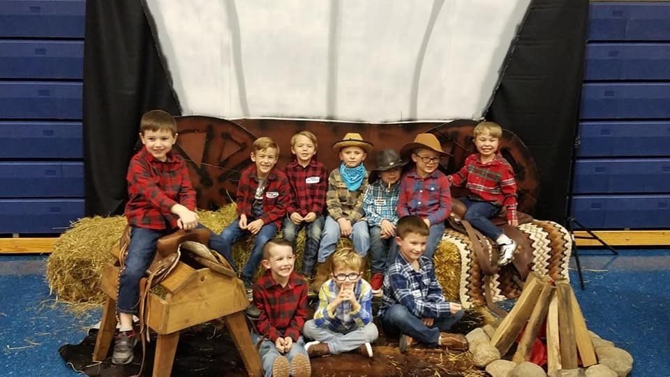 A group of young boys dressed as cowboys are posing for a picture.