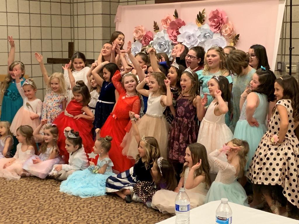 A group of little girls in dresses are posing for a picture