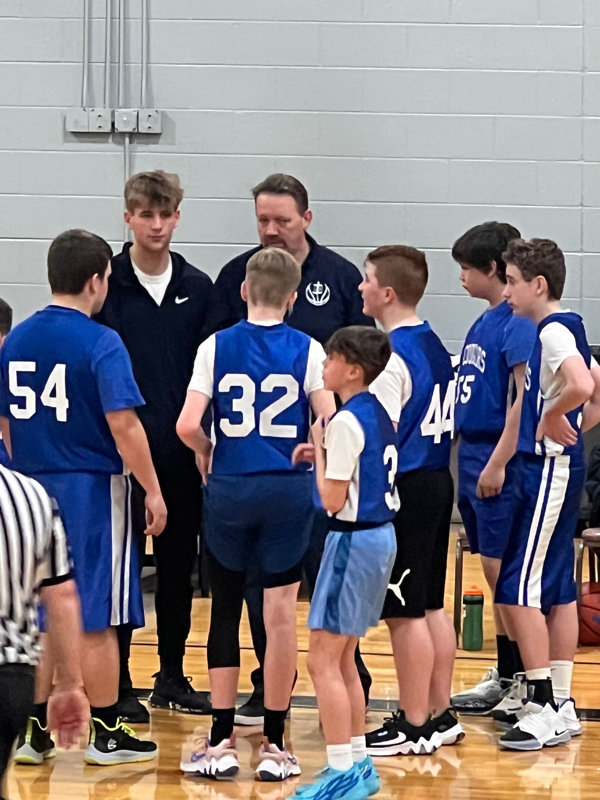 A group of kids in jerseys huddle.