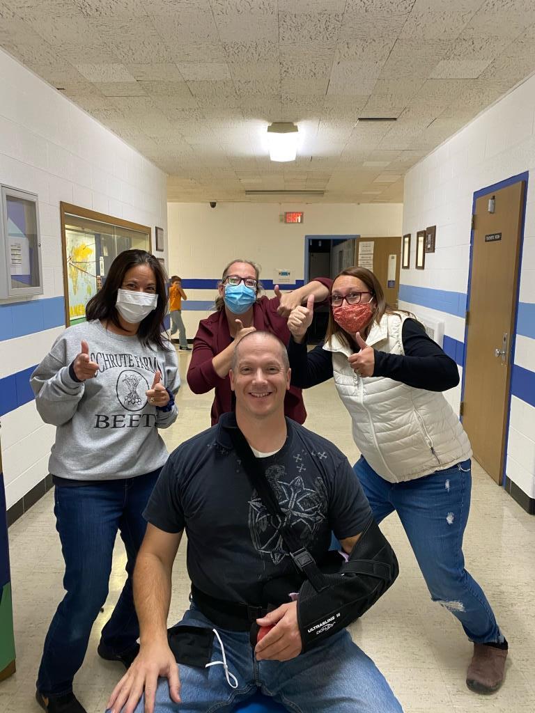 A group of people wearing face masks are posing for a picture in a hallway