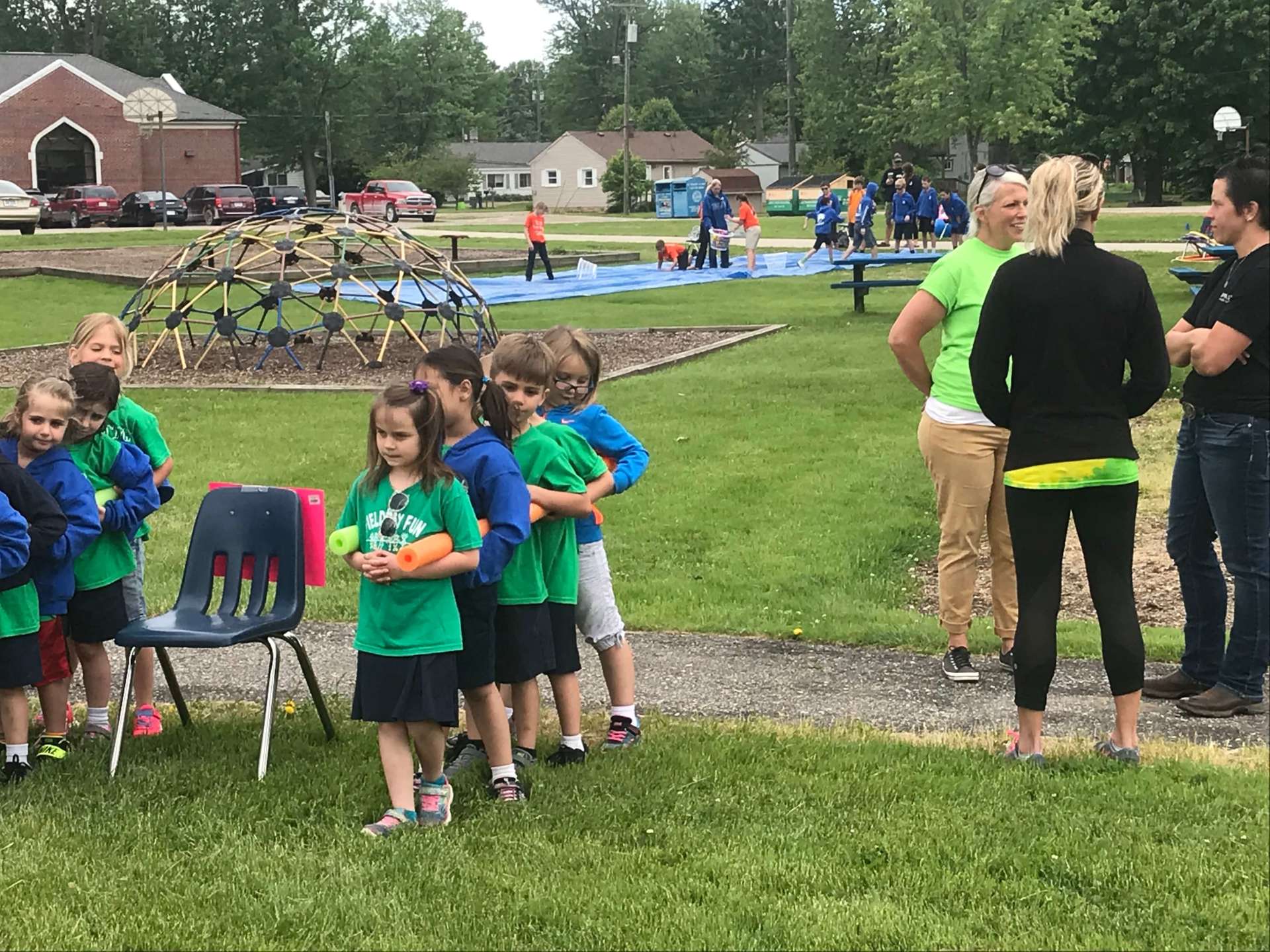 A group of children in green shirts are standing in a park