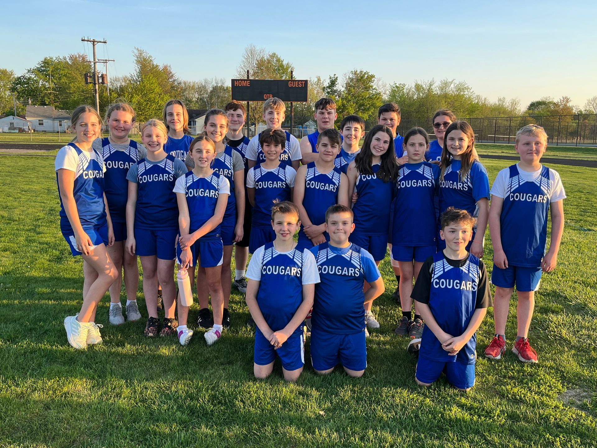 A group of kids with Cougars jerseys posing for a picture.