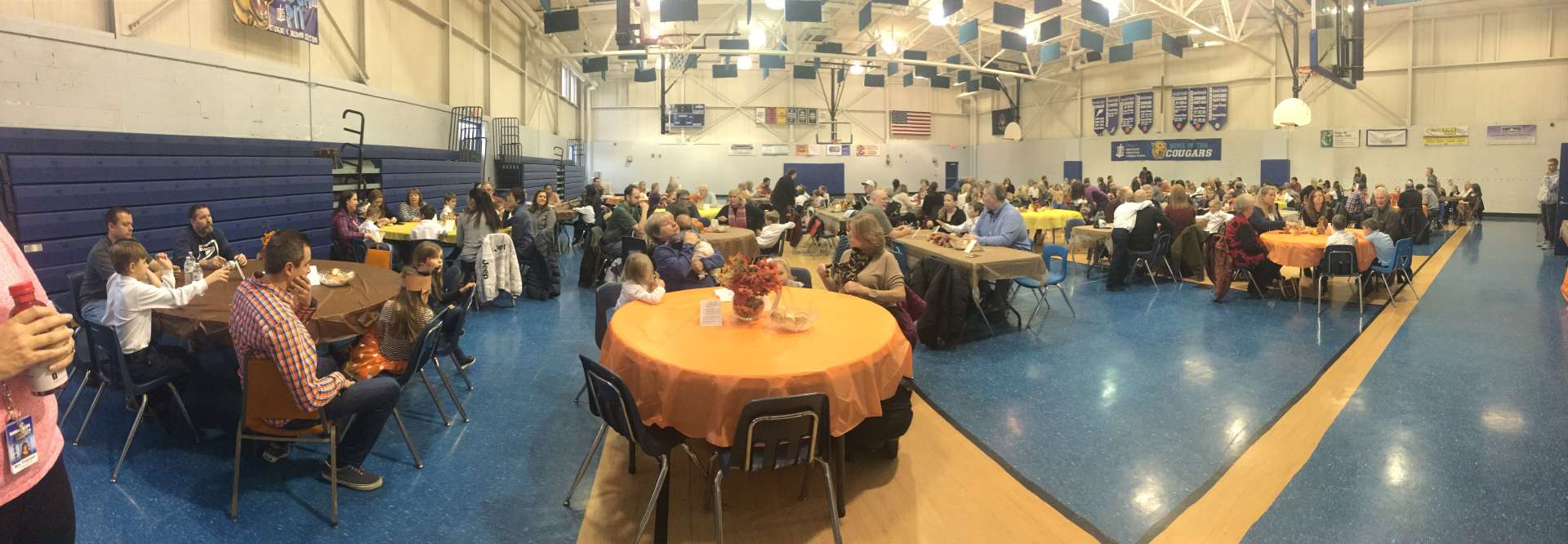A large group of people are sitting at tables in a gym
