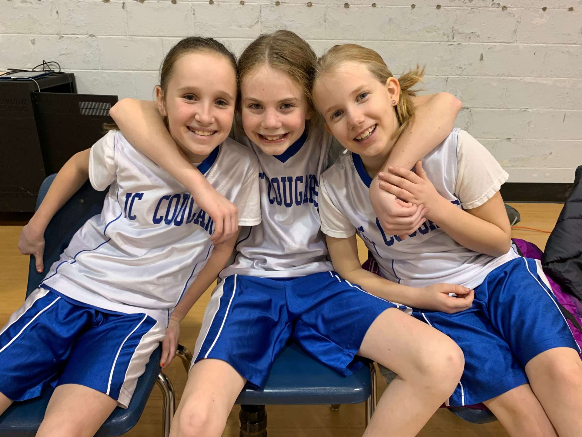 Three girls wearing jerseys that say Cougars are posing for a picture.