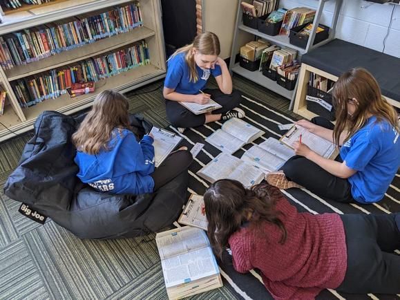 A group of MI students sitting on the floor in Immaculate Conception Catholic School library.
