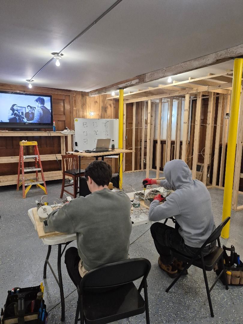 Two men are sitting at a table in a room under construction.