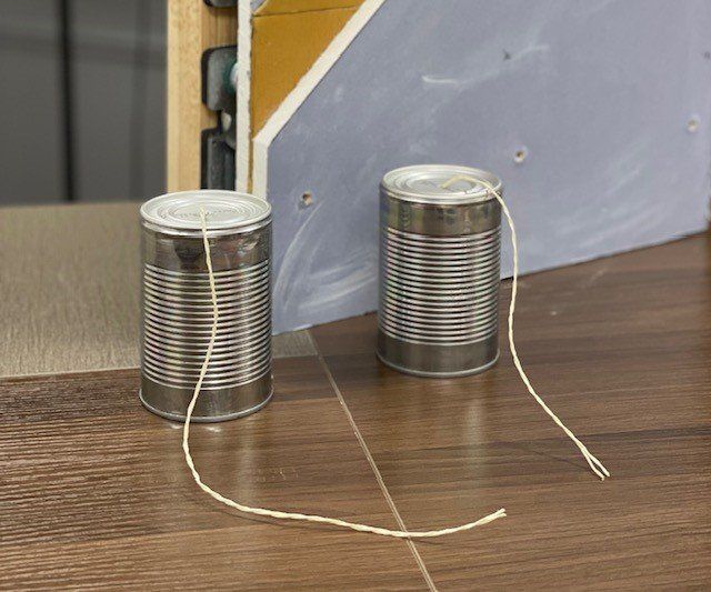 Tin cans and cut string showing decoupling when soundproofing 