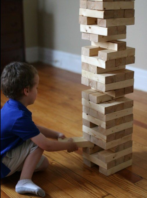 Child playing Jenga on a wooden floor