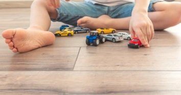 Child playing with cars on wooden floor