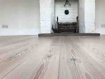 An empty room with a wooden floor and a fireplace.