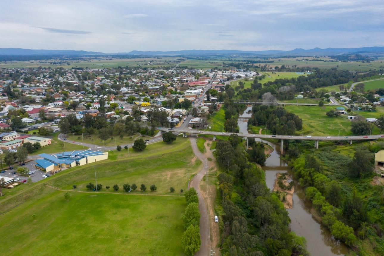 An Aerial View Of A Small Town Next To A River And A Bridge — Premier Bricks, Blocks & Pavers In Singleton, NSW