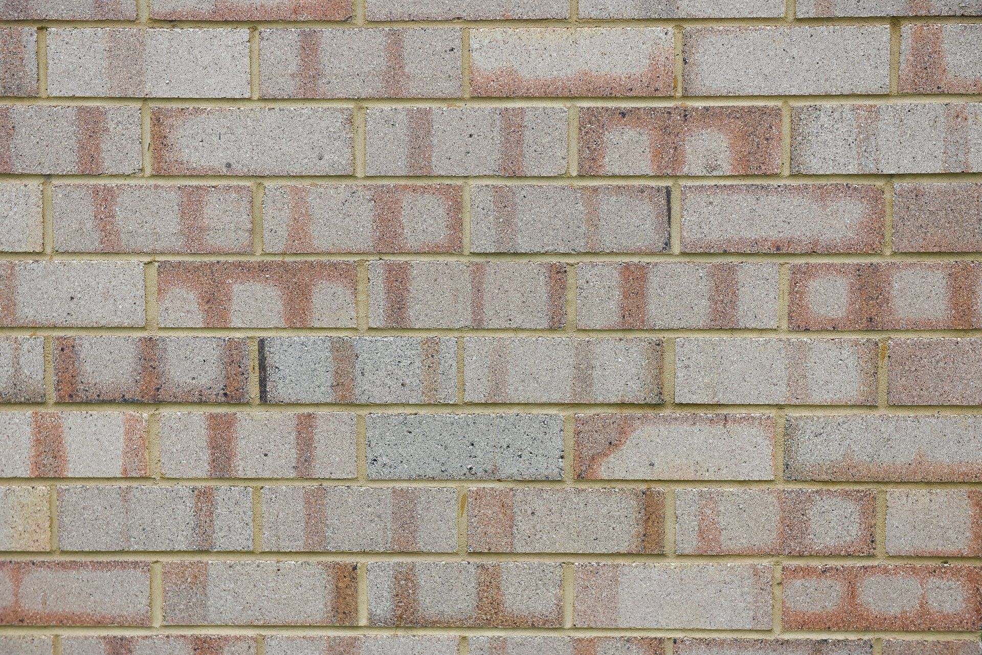 Gray and reddish brick wall with yellow mortar lines — Premier Bricks, Blocks & Pavers In Heatherbrae, NSW