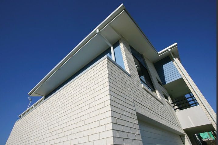 Modern white brick house with blue accents against a clear blue sky — Premier Bricks, Blocks & Pavers In Heatherbrae, NSW