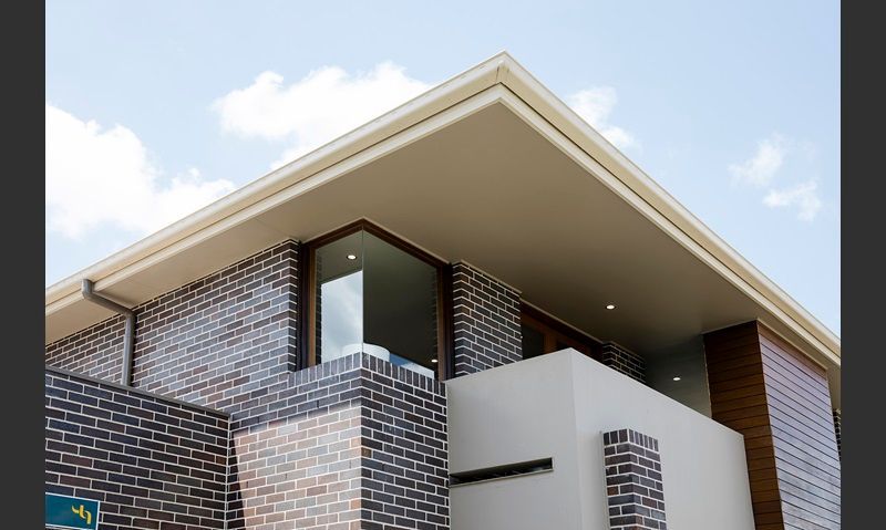 Modern brick house with a flat roof and large window against a blue sky — Premier Bricks, Blocks & Pavers In Heatherbrae, NSW