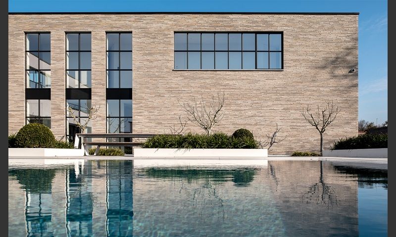 Modern brick building with long windows reflected in a calm pool — Premier Bricks, Blocks & Pavers In Heatherbrae, NSW