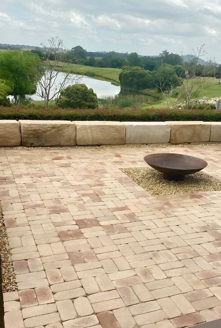 A Brick Patio With A Fire Pit And A View Of A River — Premier Bricks, Blocks & Pavers In Huntlee, NSW