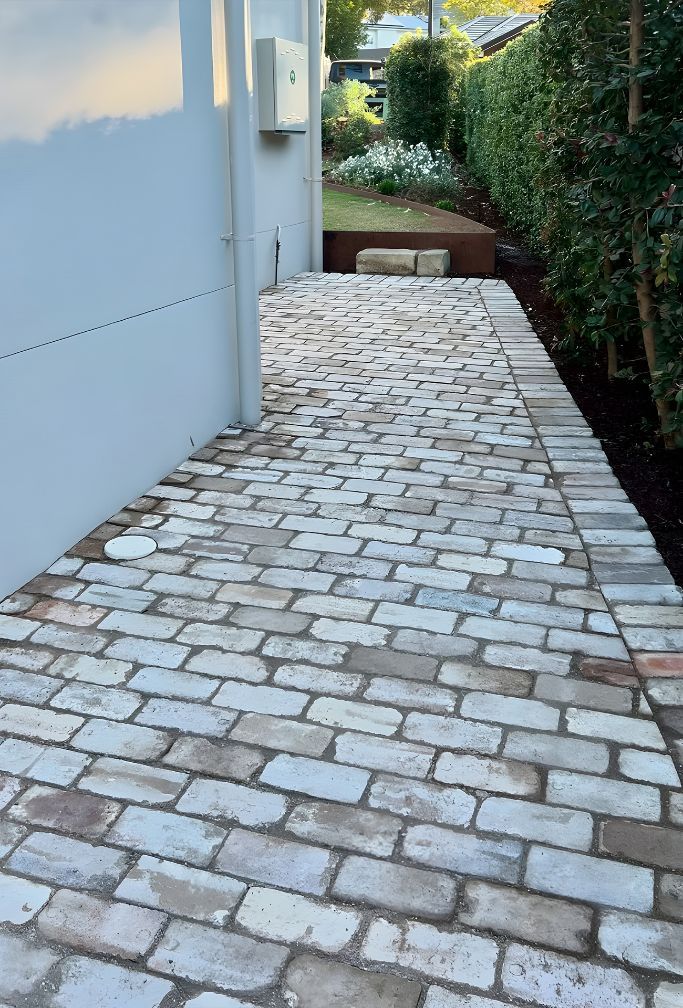 A Brick Walkway Leading To A House With A White Wall — Premier Bricks, Blocks & Pavers In Hawks Nest, NSW