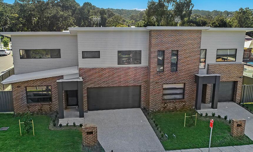 Modern brick and light gray duplex home with garages and green lawns — Premier Bricks, Blocks & Pavers In Heatherbrae, NSW