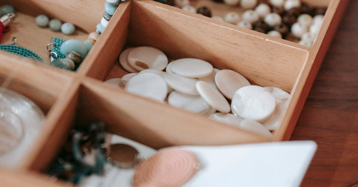 A person is holding a piece of paper in front of a wooden jewelry box filled with jewelry.