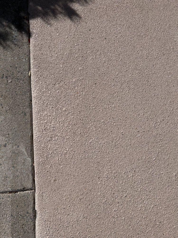 A close up of a concrete sidewalk with a tree shadow on it.