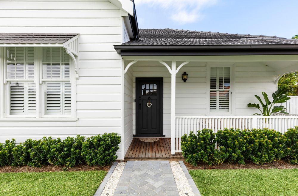 White house with a black door and porch, showcasing Elite Insulation Services' insulation for homes.