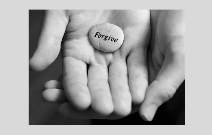 Hand Holding a Stone with a Forgive Word