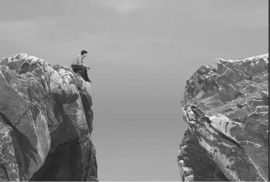 Man Sitting on the Edge of a Cliff