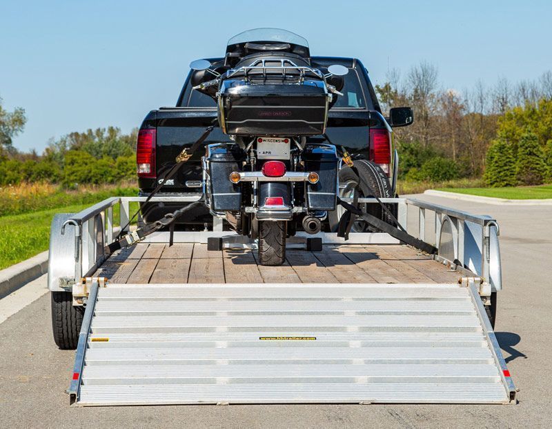 Black motorcycle secured on a trailer attached to a black truck.
