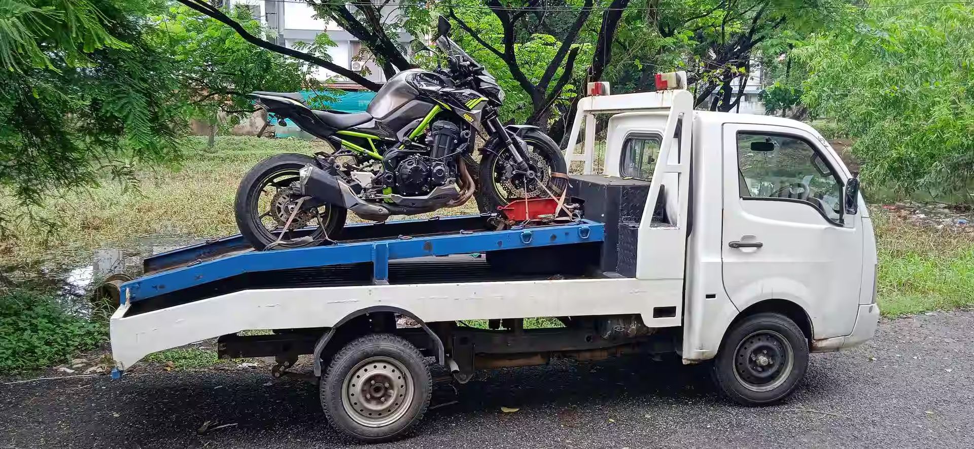 A black and green motorcycle being transported on a white flatbed truck, set against a
backdrop of